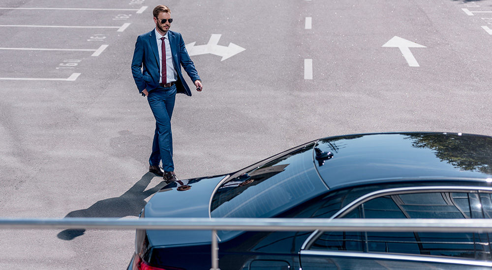 Businessman walking in a parking lot towards car.